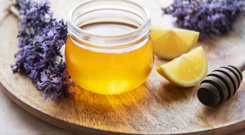 Jar with honey and fresh lavender flowers on a wooden background
