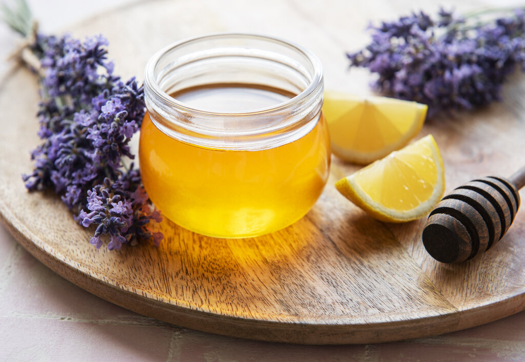 Jar with honey and fresh lavender flowers on a wooden background